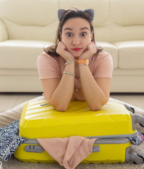 Holidays, voyage and travel concept - woman collects a yellow suitcase at home